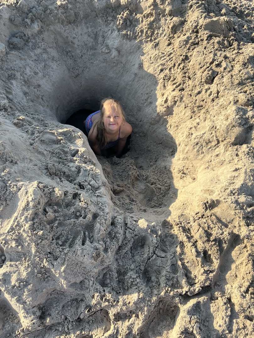Agathe accroupie en tenue blanche au coucher du soleil, observant un hérisson.